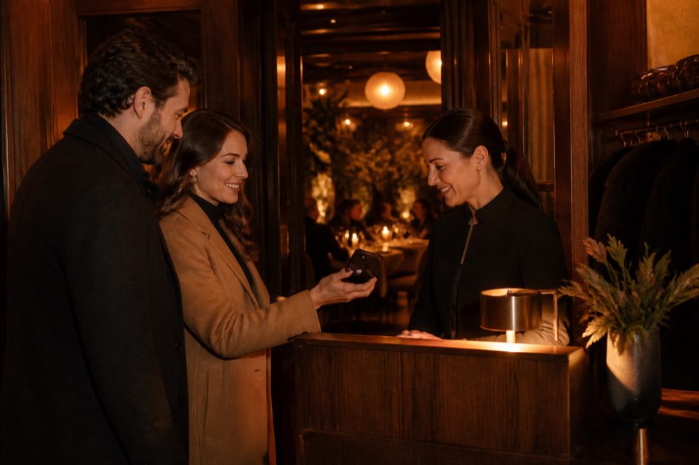 Coppia accolta all’ingresso di un ristorante mostra il telefono