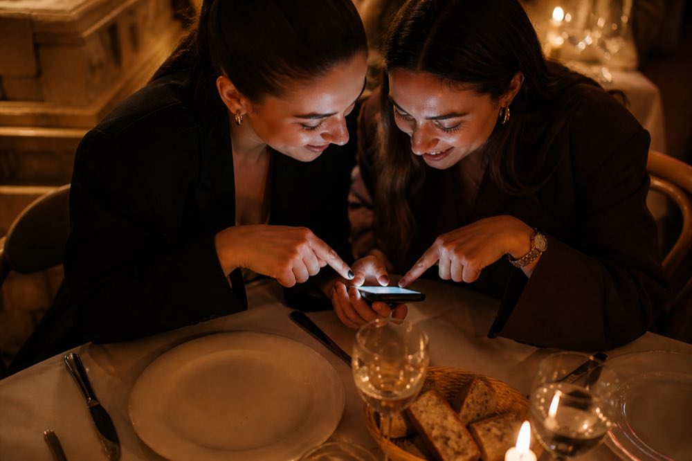 Dois amigos na mesa escolhendo juntos no celular